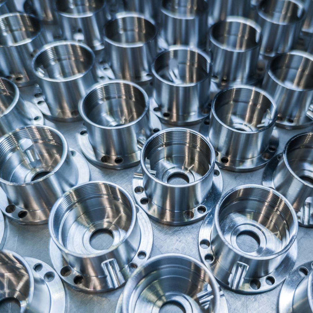 Eine große Anzahl von Metallteilen ist ordentlich auf einem Tisch angeordnet.